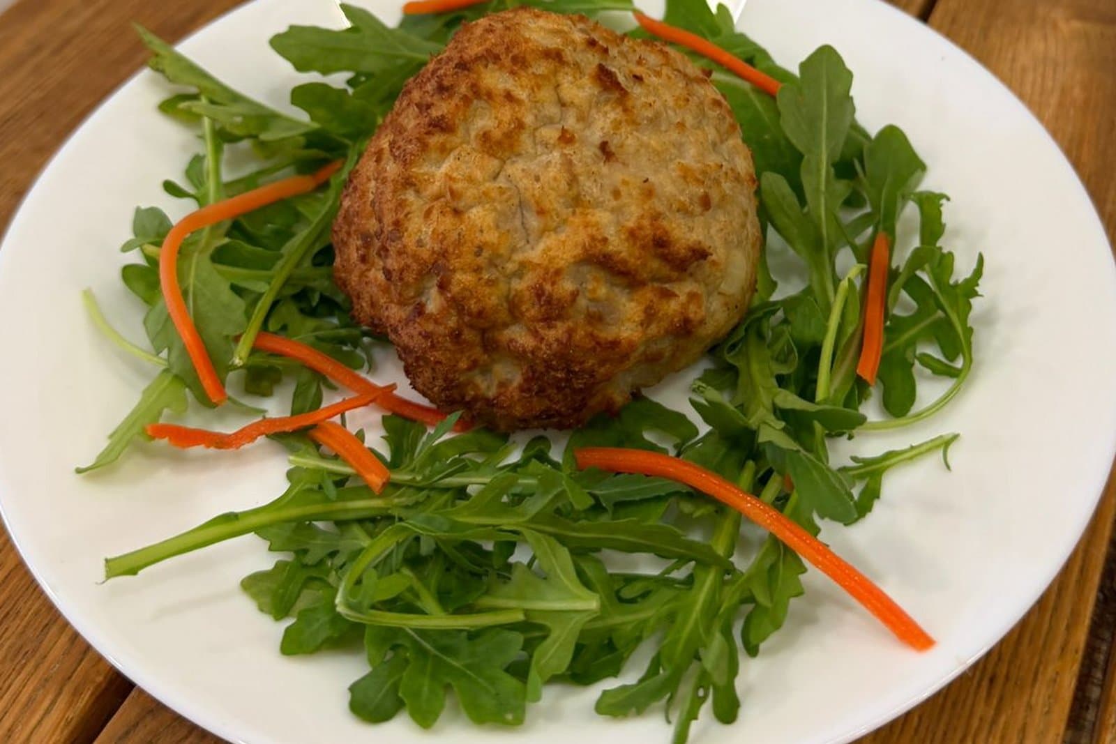 Une boulette maison servie sur un lit de roquette et de carotte